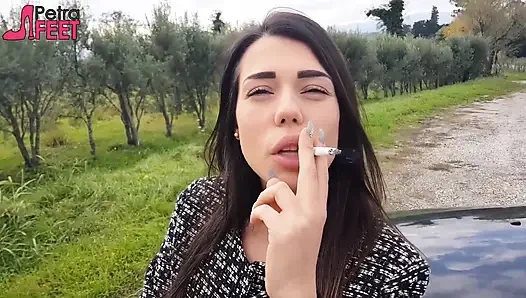 Outdoors smoking cigar from sexy brunette