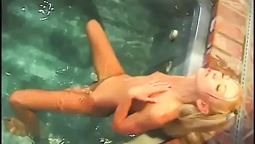 Naked blonde masturbates in hot pool while man with pantyhose on his head watches